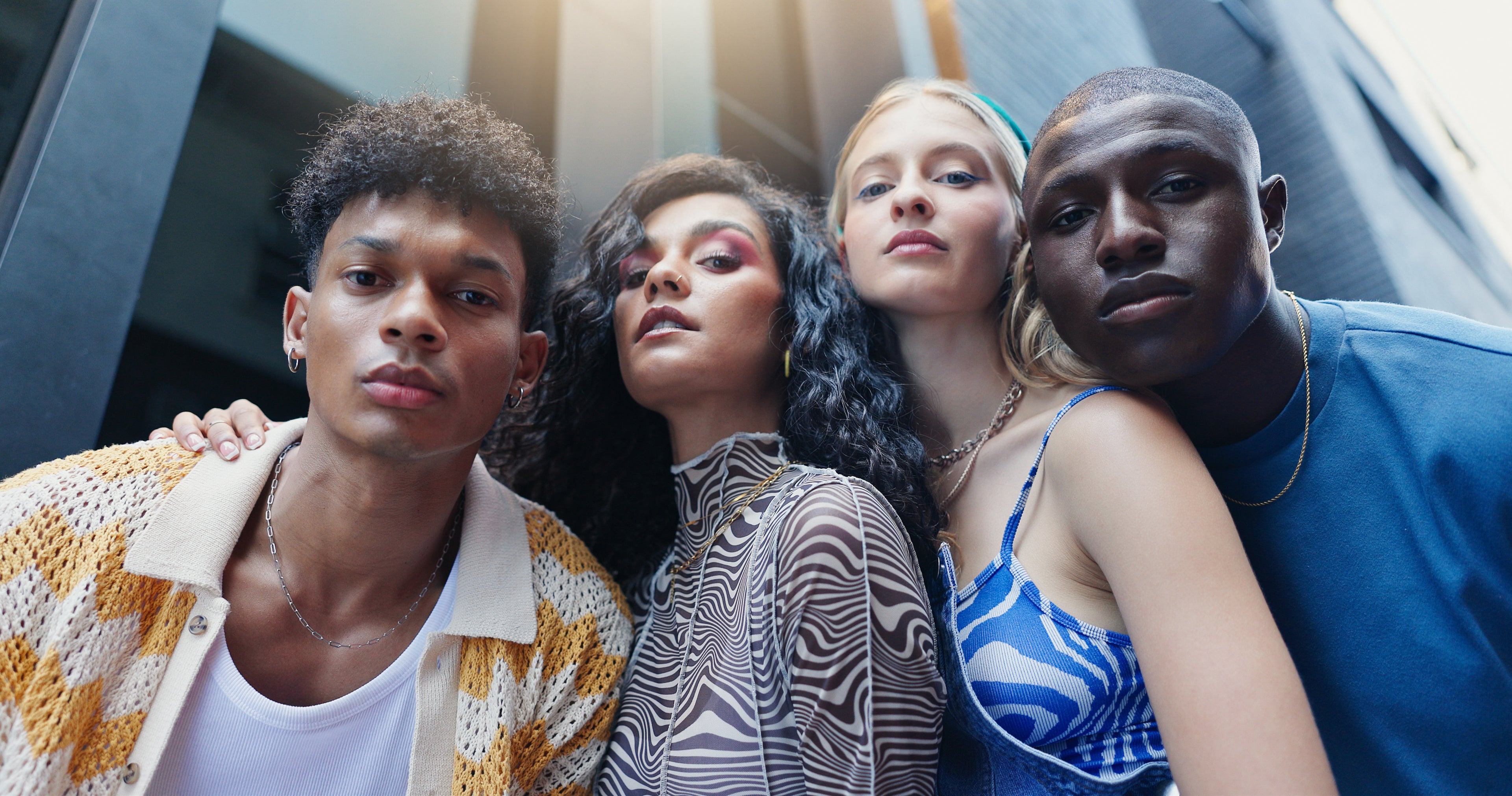 Four young adults posing together with a modern urban background